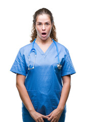 Young brunette doctor girl wearing nurse or surgeon uniform over isolated background afraid and shocked with surprise expression, fear and excited face.