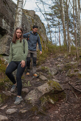Naklejka premium Young couple walking down a rocky slope during a hike in the forest in spring