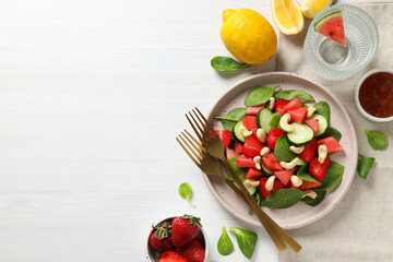 Fresh watermelon salad in a bowl with lemon and strawberries on the table