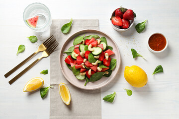 Fresh watermelon salad in a bowl with lemon and strawberries on the table