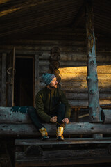 man sitting on the entrance of a stuga in the middle of the forest