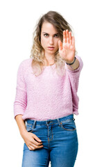 Fototapeta premium Beautiful young blonde woman over isolated background doing stop sing with palm of the hand. Warning expression with negative and serious gesture on the face.