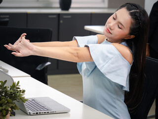 Asian businesswoman looking at work on laptop computer with satisfaction and stretching arms in the...