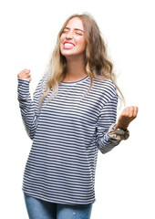 Obraz premium Beautiful young blonde woman wearing stripes sweater over isolated background very happy and excited doing winner gesture with arms raised, smiling and screaming for success. Celebration concept.