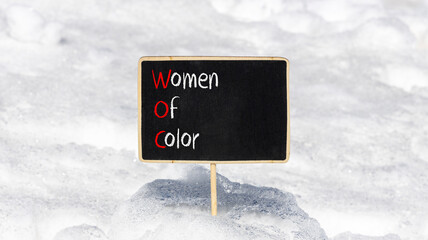 WOC women of color symbol. Concept words WOC women of color on beautiful yellow blackboard....