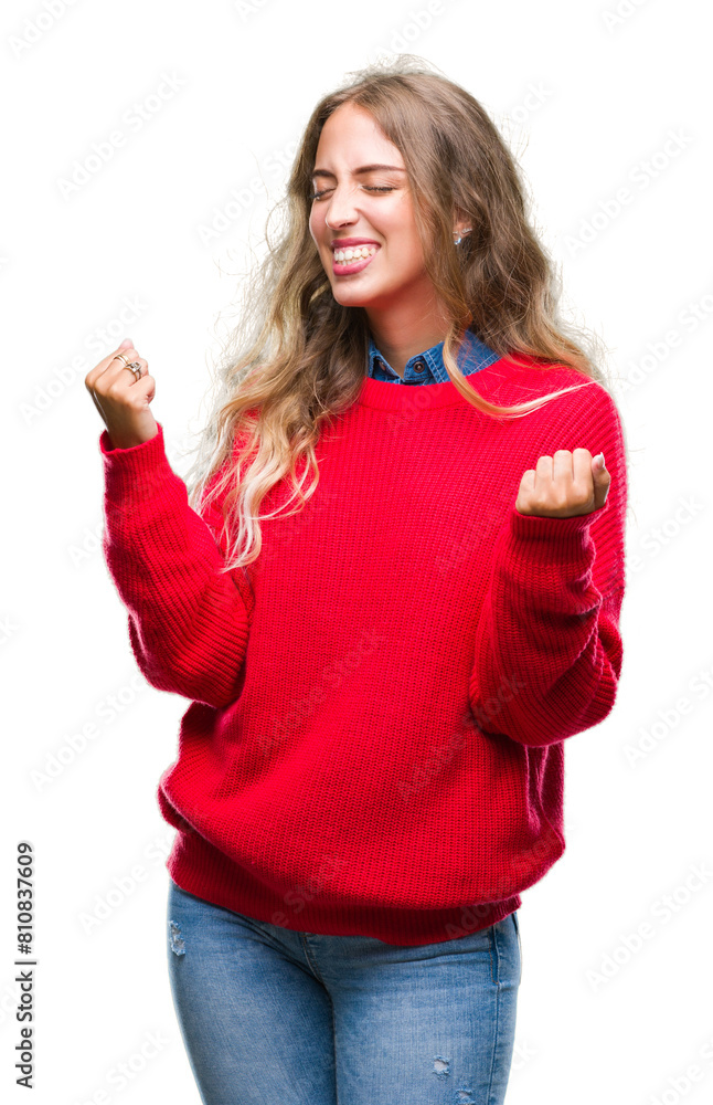 Sticker Beautiful young blonde woman wearing winter sweater over isolated background very happy and excited doing winner gesture with arms raised, smiling and screaming for success. Celebration concept.