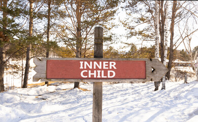 Inner child symbol. Concept words Inner child on beautiful wooden road sign. Beautiful forest snow blue sky background. Psychological, motivational inner child concept. Copy space.
