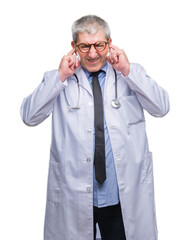 Handsome senior doctor man over isolated background covering ears with fingers with annoyed expression for the noise of loud music. Deaf concept.