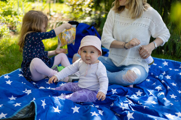 mother with her daughters outdoors, baby excitement, spending time in the garden among nature, sun,...