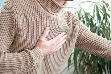 young man experiences experiences sudden chest pain behind sternum, clutching chest, Arterial...