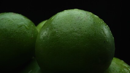 Slices of lime are meticulously arranged in a pile, set against a black background. Each lime slice...