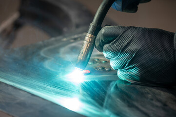 Close-up of welder's hand using welding torch on metal surface