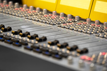 Close-up view of professional audio mixer control panel with knobs and switches