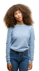 African american woman wearing a sweater making fish face with lips, crazy and comical gesture. Funny expression.