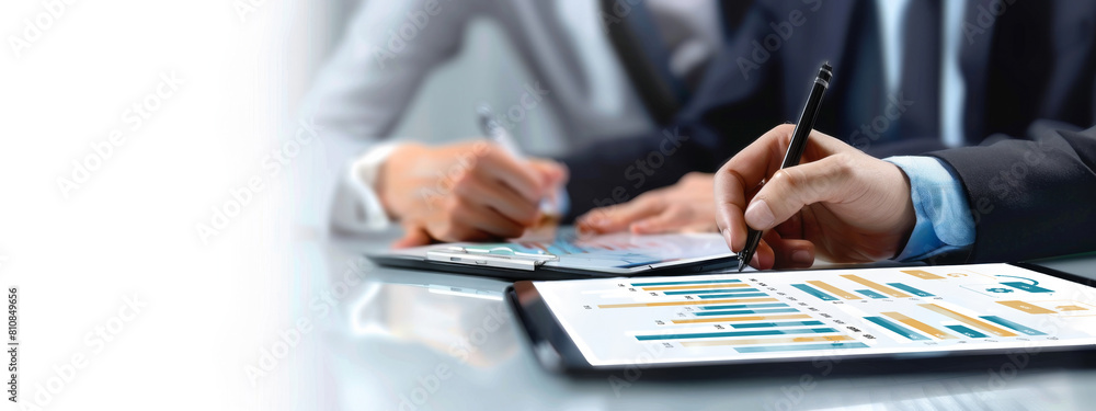 Poster two people are writing on a table with a tablet. the tablet has a graph on it. the people are wearin