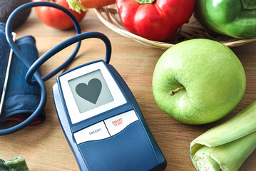 Blood pressure monitor with heart on screen and vegetables around