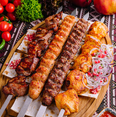 Appetizing presentation of assorted grilled barbecue skewers on a wooden board with fresh vegetables