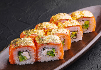 Luxury gold leaf sushi rolls on dark plate