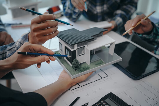 Team of engineers in a meeting, drawing blueprints for condo, apartment, and house construction. Negotiating costs with contractors, bidding, bargaining, and cooperating on construction sites.