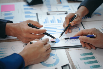A professional business team meeting in formal suits, working at desks with financial papers,...