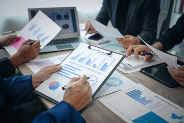A professional business team meeting in formal suits, working at desks with financial papers,...