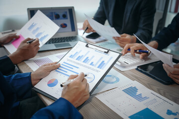A professional business team meeting in formal suits, working at desks with financial papers, calculators, and laptops. Close-up of hands. Discussion on revenue, brand, sales, agenda, capital