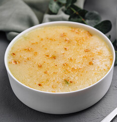 Creamy corn soup with herbal tea on gray table