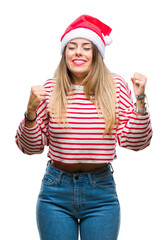 Young beautiful woman wearing christmas hat over isolated background very happy and excited doing winner gesture with arms raised, smiling and screaming for success. Celebration concept.