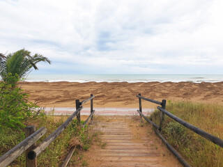 Wooden path through the sandy shore to the sea.