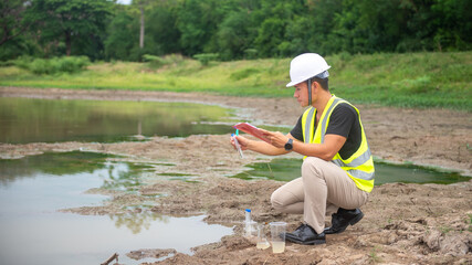 Environmental engineer Sit down next to a well and looking at the glass tube of water sample to...