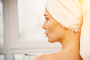 Young serene relaxed woman in spa bath towel drinking hot beverage tea coffee after taking shower...