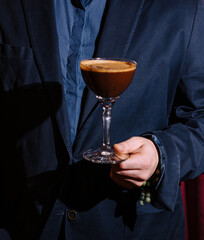 Man in suit holding espresso martini cocktail