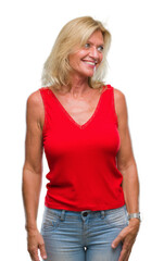 Middle age blonde woman over isolated background looking away to side with smile on face, natural expression. Laughing confident.