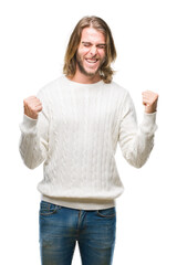 Young handsome man with long hair wearing winter sweater over isolated background very happy and excited doing winner gesture with arms raised, smiling and screaming for success. Celebration concept.