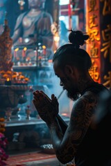 Naklejka premium A man with tattoos praying in a temple, suitable for religious and spiritual concepts