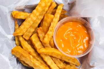 close up of french fries and cheese sauce on white paper.Fast food.