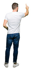 Handsome man wearing casual white t-shirt Posing backwards pointing behind with finger hand