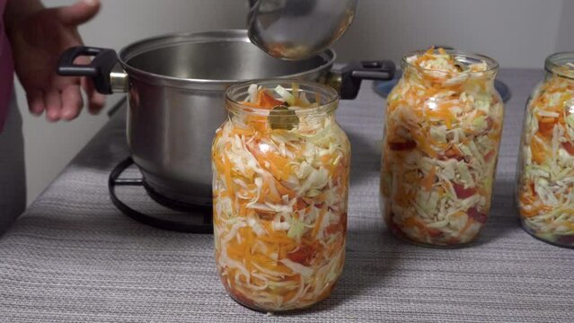 Pour marinade into jars with cabbage, a woman pours marinade into jars with cabbage, prepare a salad of cabbage and pepper