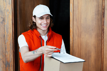 Friendly Delivery Man Handing Over Parcel In Casual Outfit, Smiling Young Male With White Cap And...