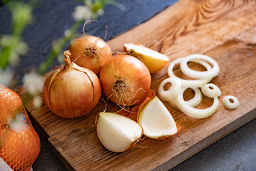 Cebollas marrones y rodajas sobre tabla de cortar de madera. Fondo de alimentos saludables.