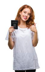 Naklejka premium Young beautiful woman holding passport of italy over isolated background happy with big smile doing ok sign, thumb up with fingers, excellent sign