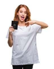 Fototapeta premium Young beautiful woman holding passport of united states of america over isolated background very happy pointing with hand and finger
