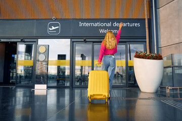 A traveler is late and runs into the international departures terminal. Joyfully raising her hand,...