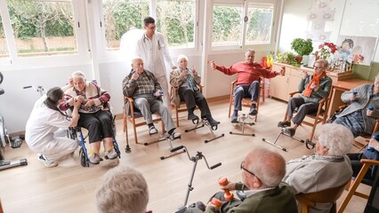 Friendly caregivers assist senior people in exercise at nursing home
