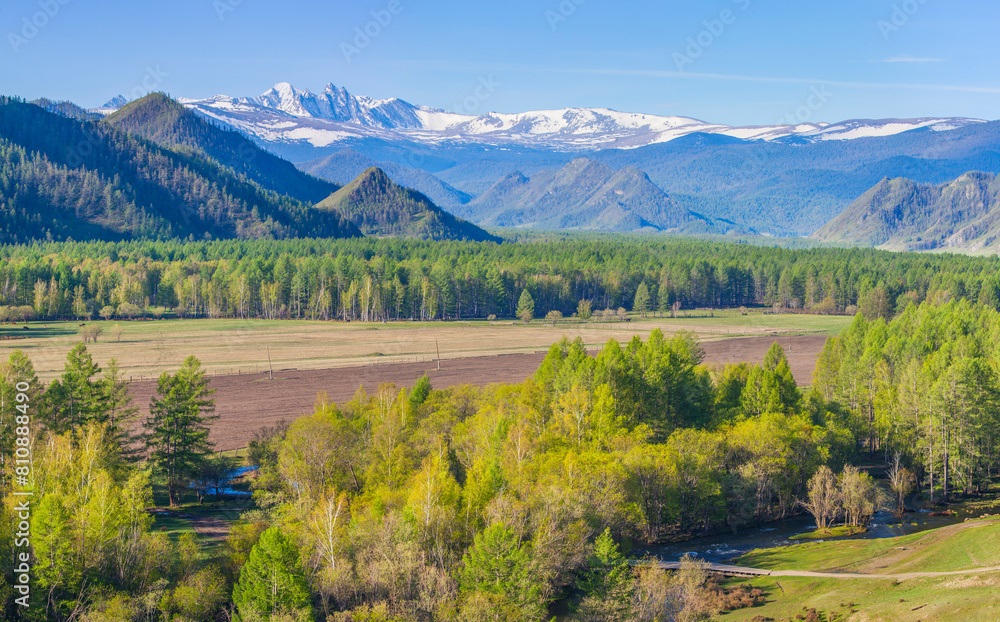 Sticker Mountain valley on a spring sunny day, snow on the peaks and greenery	