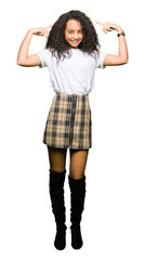 Young beautiful girl with curly hair wearing casual white t-shirt Smiling pointing to head with both hands finger, great idea or thought, good memory