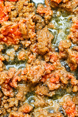 fried minced meat in a frying pan close-up, vertical photo