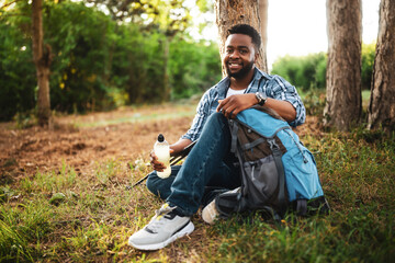 Young hiker drinking energy drink while enjoys resting in nature.	