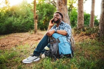 Young hiker using mobile phone while enjoys resting in nature.	