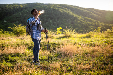 Young man enjoys hiking and drinking energy drink.	